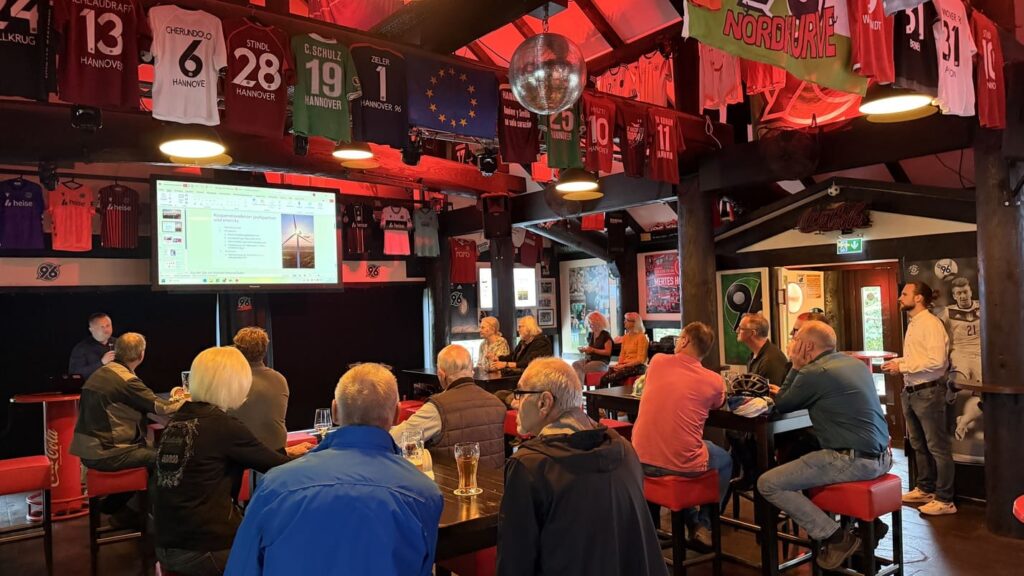 Teilnehmende der Jahreshauptversammlung 2026 des enercity profipartner e. V. verfolgen eine Präsentation in der mit Fußballtrikots geschmückten Nordkurve Hannover.
